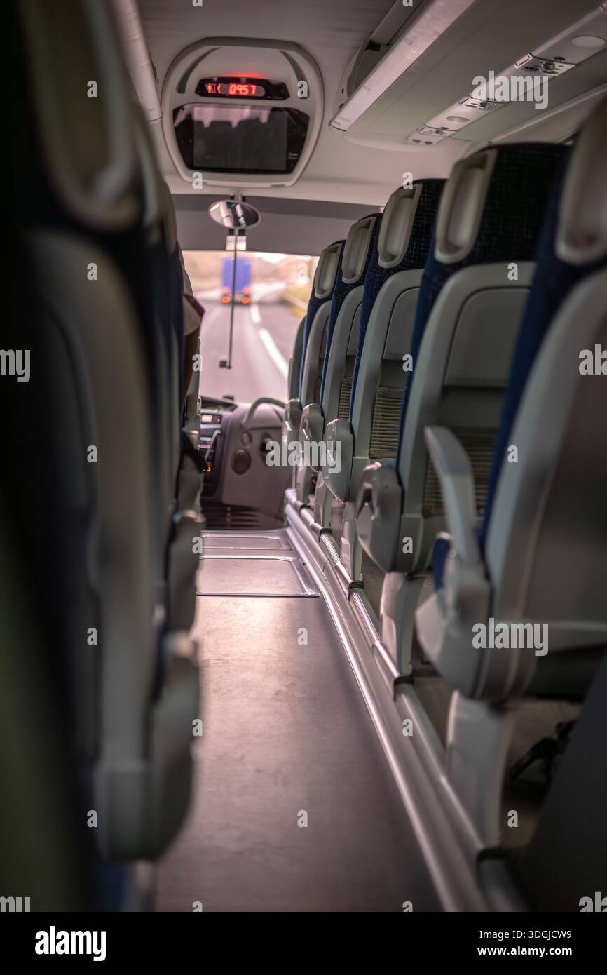 Ein leerer Gang in einem Intercity-Bus oder -Bus mit Blick auf den Fahrersitz und die Straße vor Ihnen. Ein Konzept für Reisen, öffentliche Verkehrsmittel und das Stockfoto