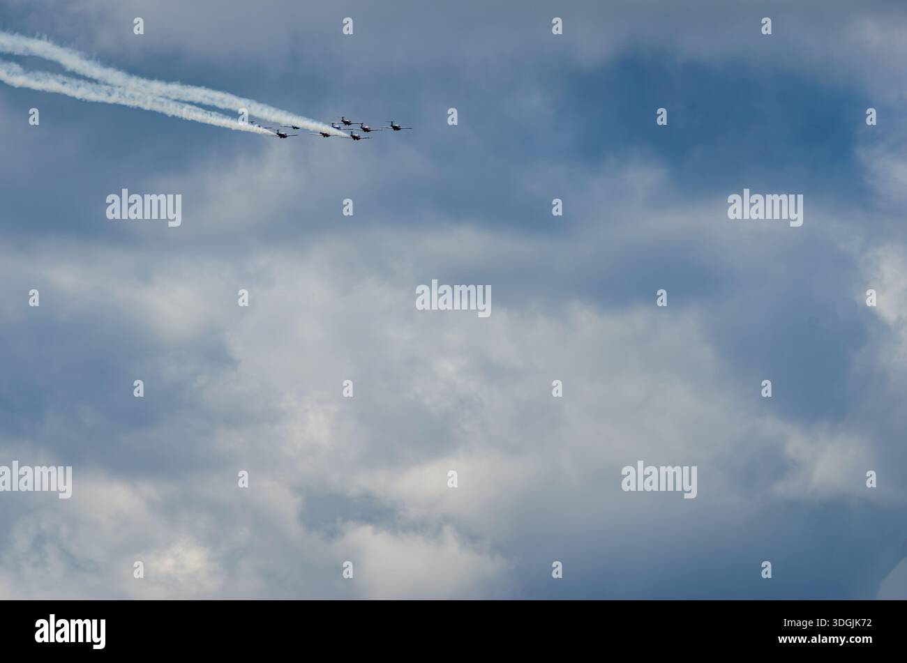 Kampfjet-Formation hoch oben am Himmel über Sturmwolken mit zwei Jet-Trails hinter ihnen an einem Sommertag. Stockfoto