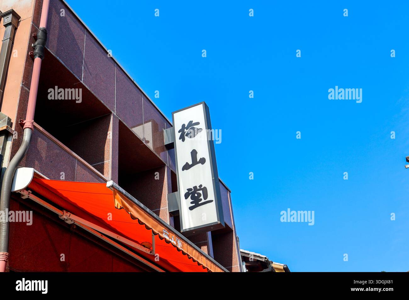 Japanisches Schaufensterschild mit Kanji-Zeichen vor blauem Himmel Stockfoto