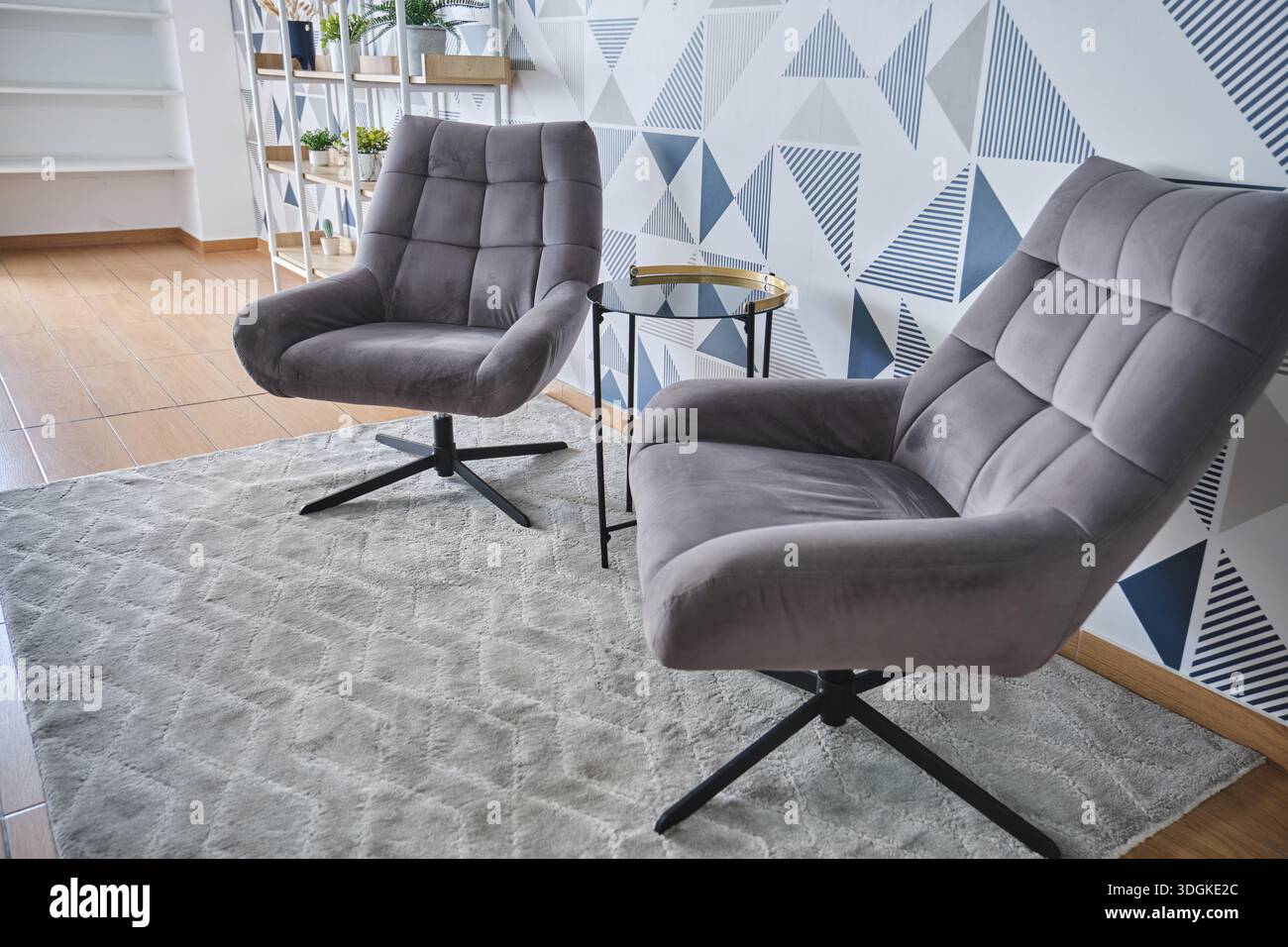 Zwei graue Drehsessel mit einem Beistelltisch auf einem Teppich in einem modernen Wohnzimmer Stockfoto