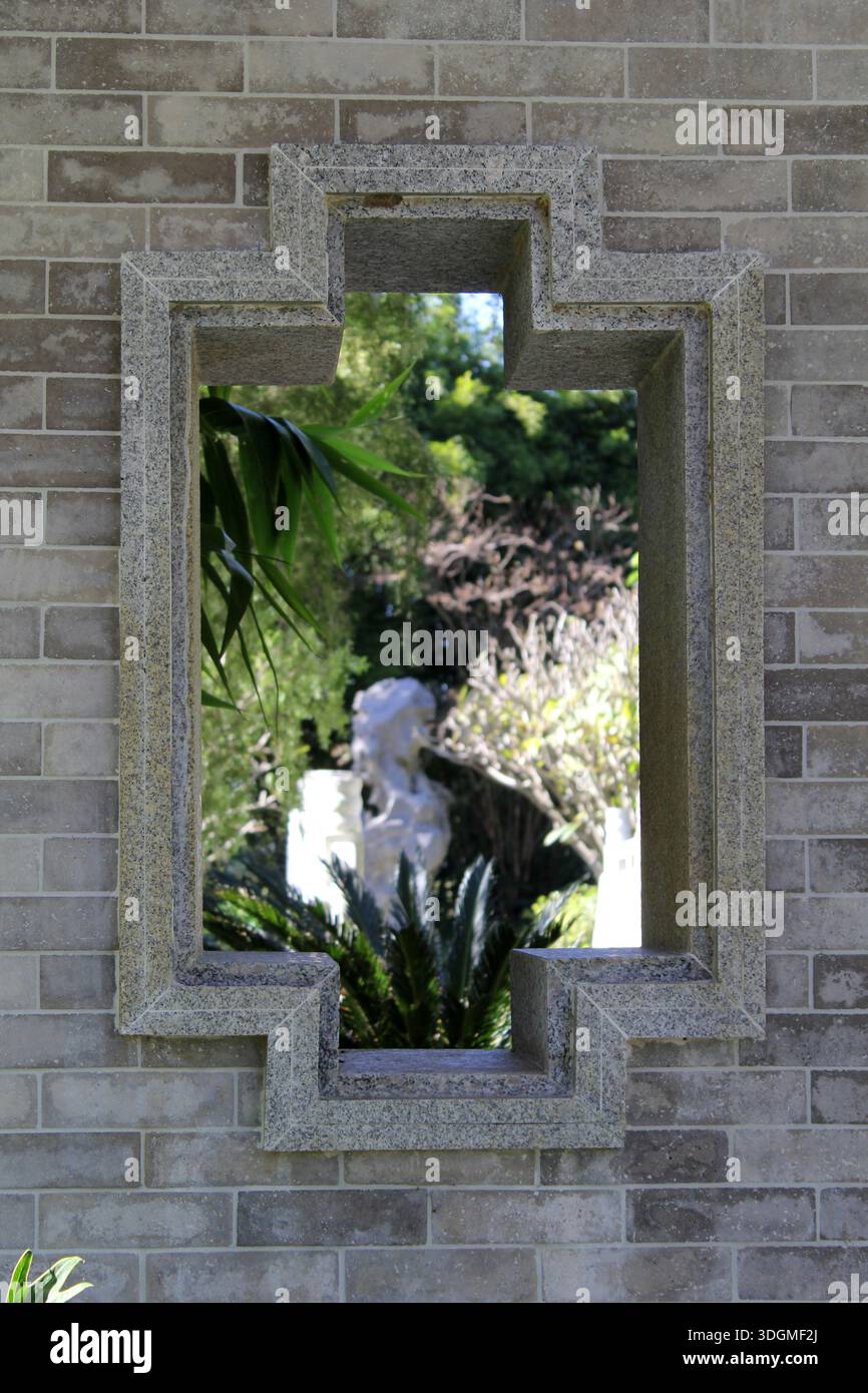 Fenster in einer Ziegelsteinmauer mit Blick auf einen Garten Stockfoto