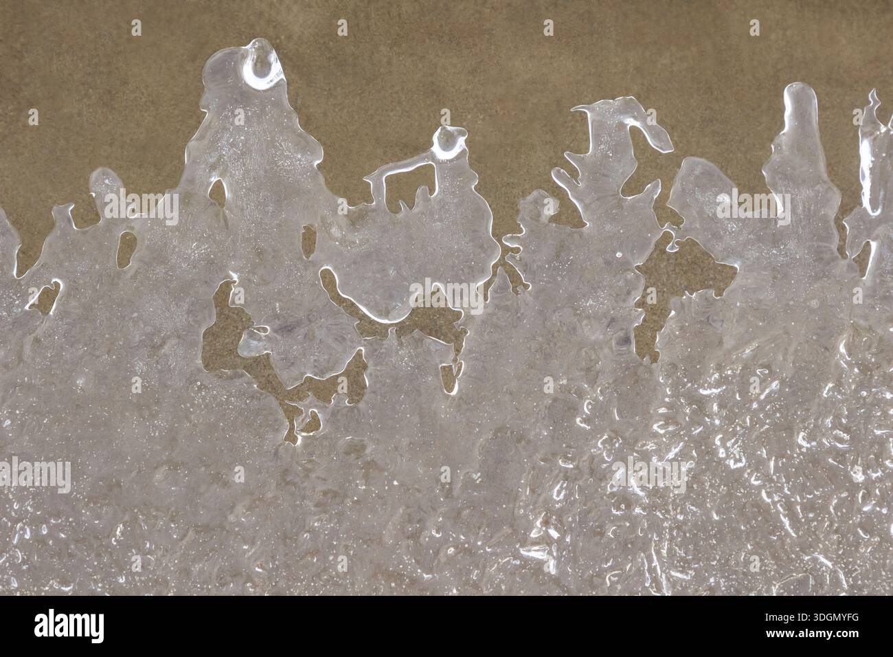 Gemusterter Eisrand auf dem Wasser. Sand auf dem Flussgrund. Draufsicht Stockfoto