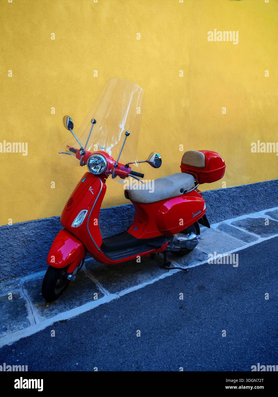 Roter italienischer Roller parkte in der Nähe des Hauses mit gelber Mauer an der Straße Stockfoto