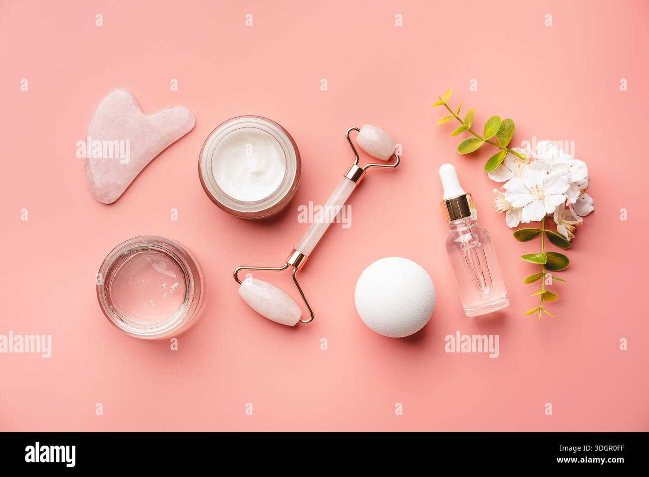 Jade-Gesichtsrollen und Gua-Sha-Steine für Beauty-Gesichtsmassage-Therapie, Artikel für die häusliche Behandlung mit Skin Care Anti-Aging-Tools, Gesichtsserum und Feuchtigkeitscreme auf rosa Hintergrund Stockfoto