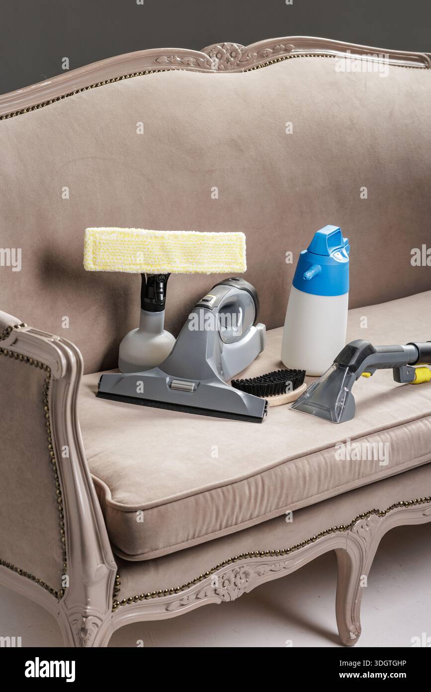 Closeup Studio Aufnahme der Polstervakuumdüse, Bürste und Sprühflasche auf Sofa für Reinigungsservice Website Banner oder Anzeige über Fleckenentfernung. Stockfoto