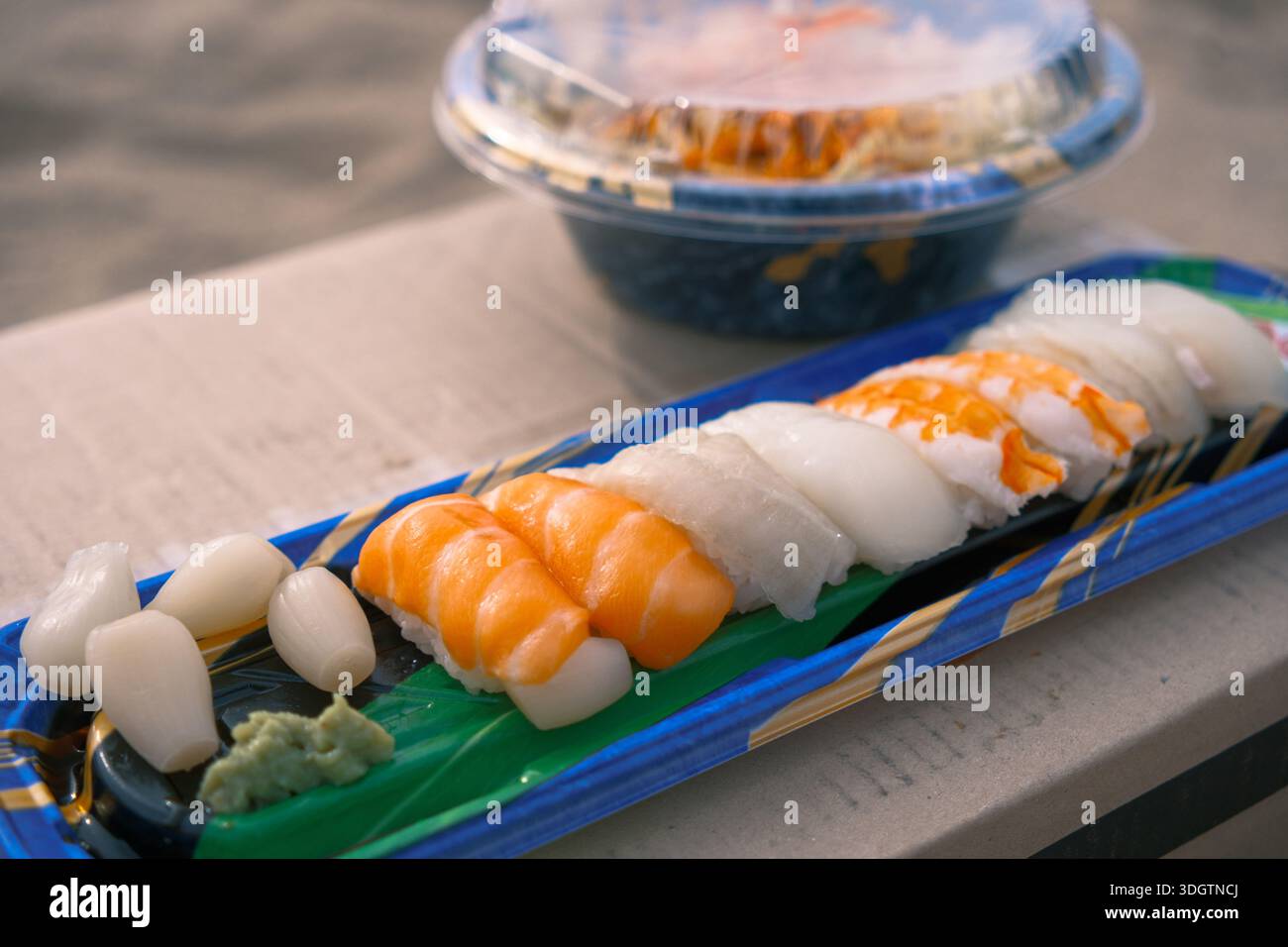 Abgepacktes Nigiri-Sushi mit Lachs und Tintenfisch, serviert in einem Plastiktablett unter natürlichem Tageslicht Stockfoto