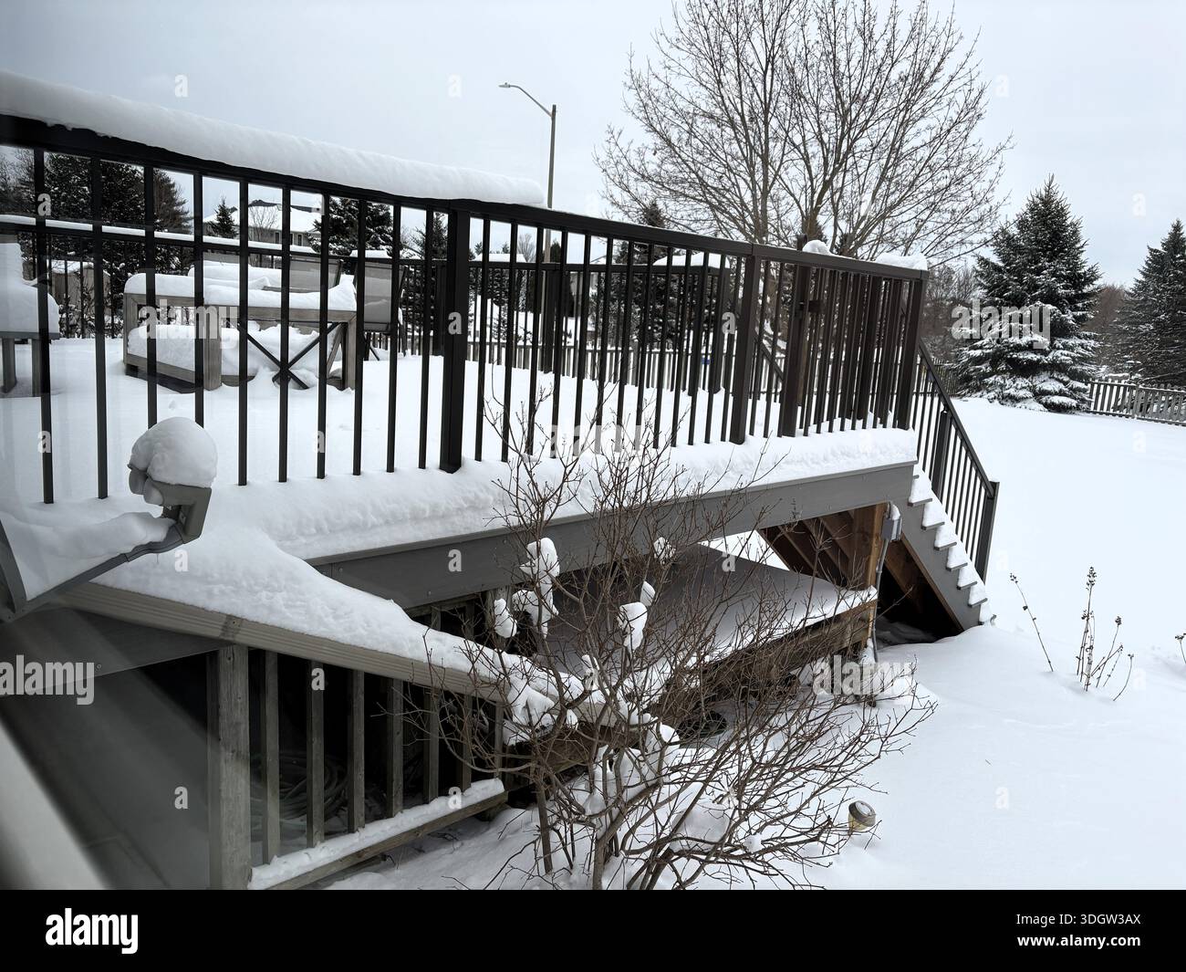 Frischer weißer Schnee baut sich auf den Terrassenmöbeln auf einer Hinterhof-Veranda auf und signalisiert den Beginn des Winters. Stockfoto