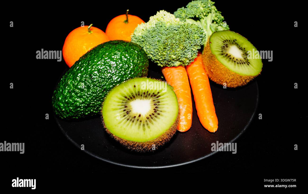 Auswahl an frischem Bio-Gemüse und Obst einschließlich Avocado Kiwi Brokkoli und Karotten für einen gesunden Lebensstil. Stockfoto