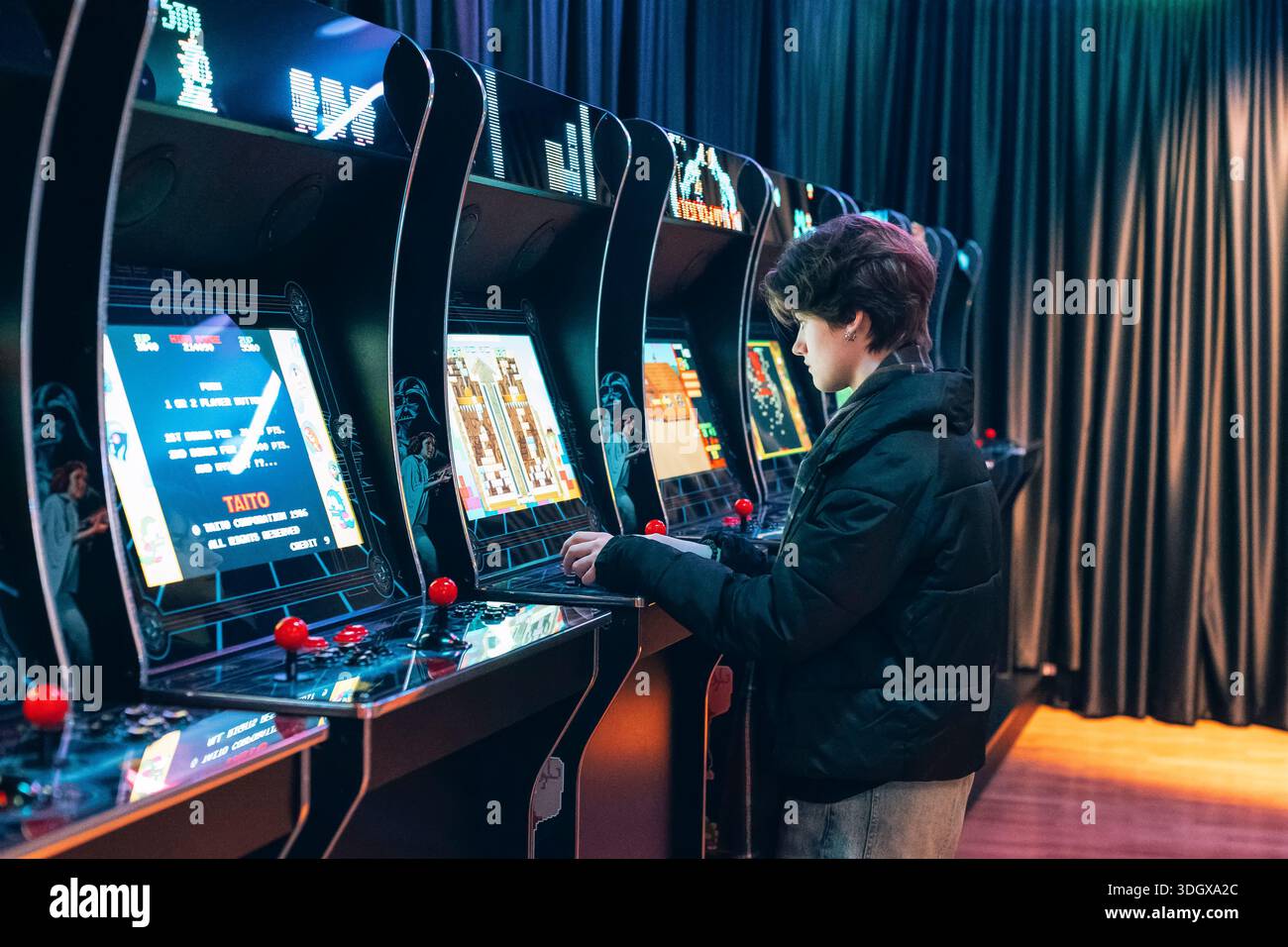 Zagreb Kroatien - 10. Januar 2026: Teenager spielen klassische Spielautomaten in der Spielhalle mit beleuchteten Bildschirmen. Stockfoto
