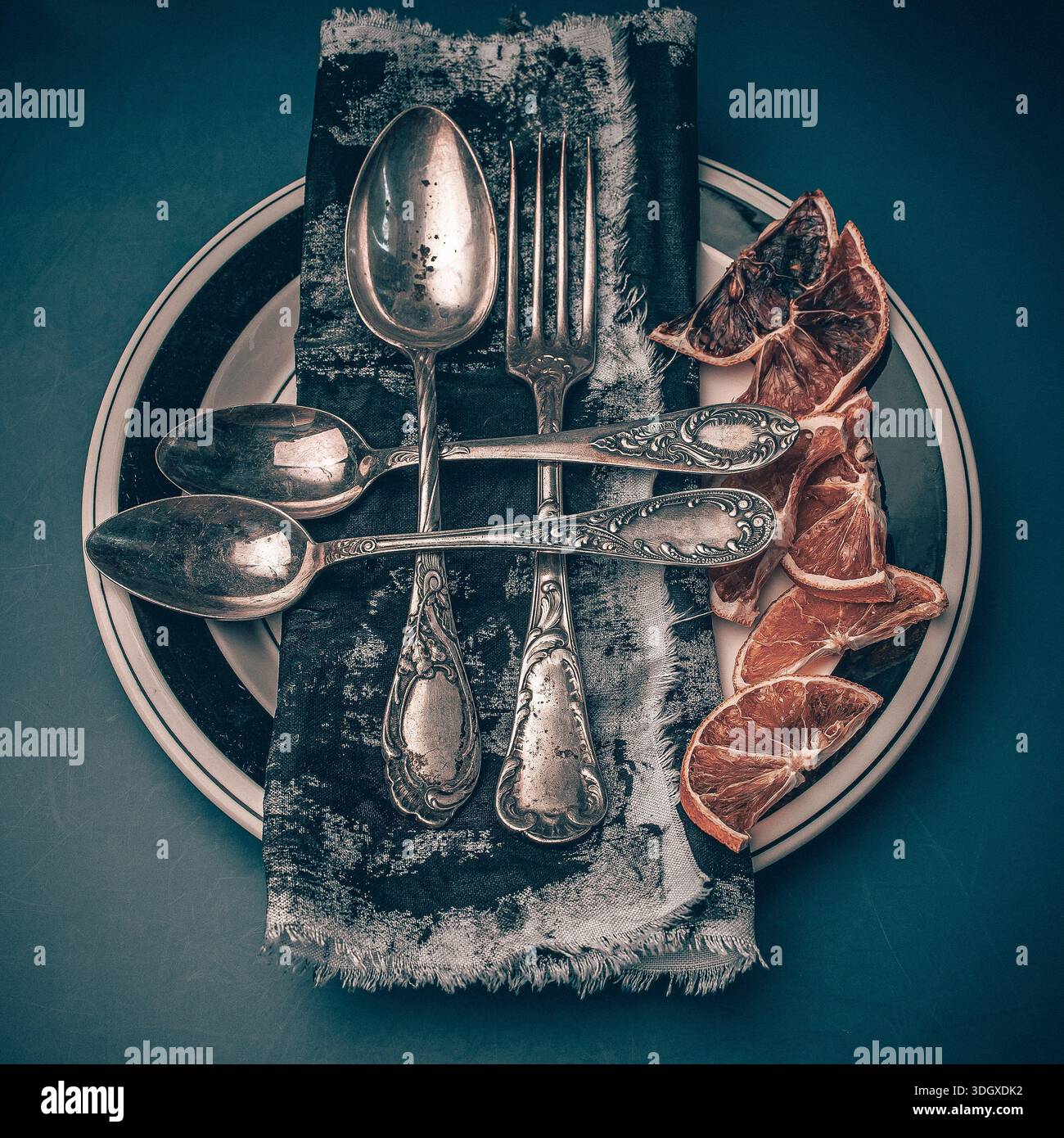 Vintage Küchenbesteck Gabeln auf dunklem rustikalem Hintergrund mit verschiedenen trockenen Orangen, Blick von oben. Besteckset in antikem Silber, kunstvolles Design. Stockfoto