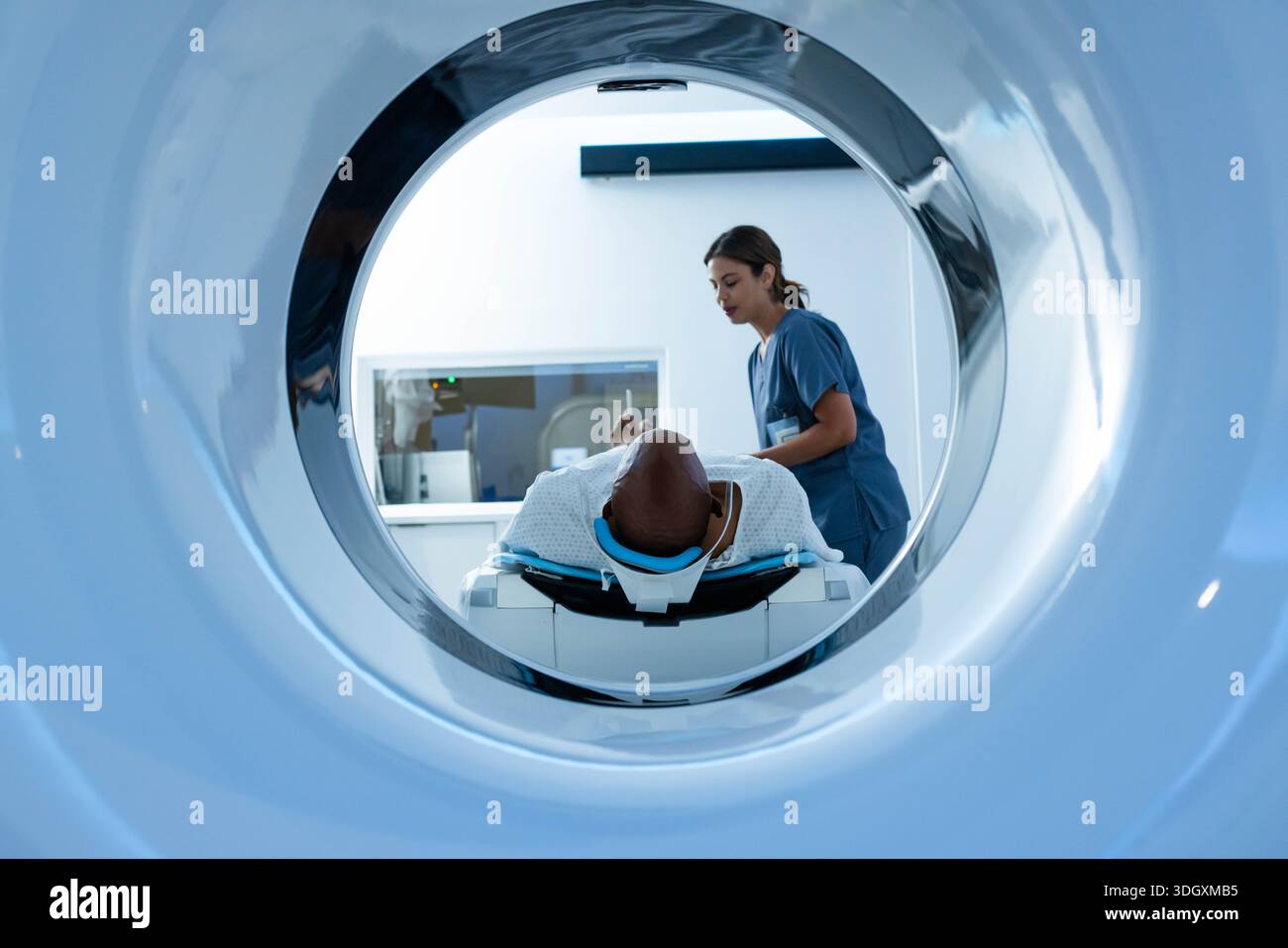 Afroamerikanischer Patient, der in der Scannerbohrung liegt, mit blauer Kopfstützentechnologie in der Peelings-Kontrollkonsole Stockfoto