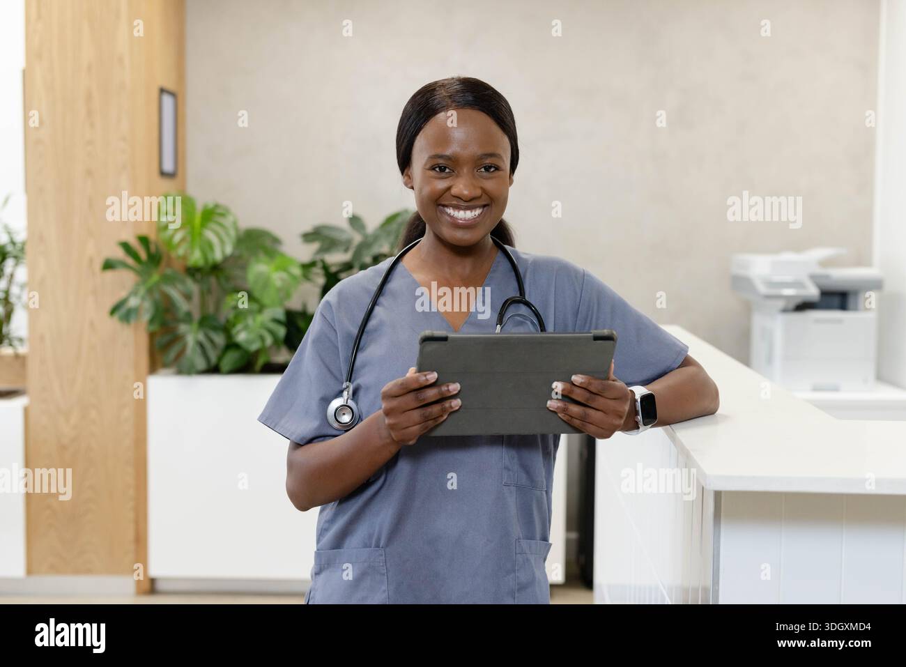 Erwachsene afrikanische Frau, die am Empfang der Klinik steht, trägt Peelings mit Tablettenstethoskop-Uhr Stockfoto