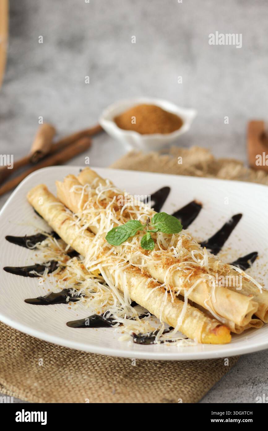 Knusprige Bananenbrötchen mit geriebenem Käse und Schokoladensauce Stockfoto