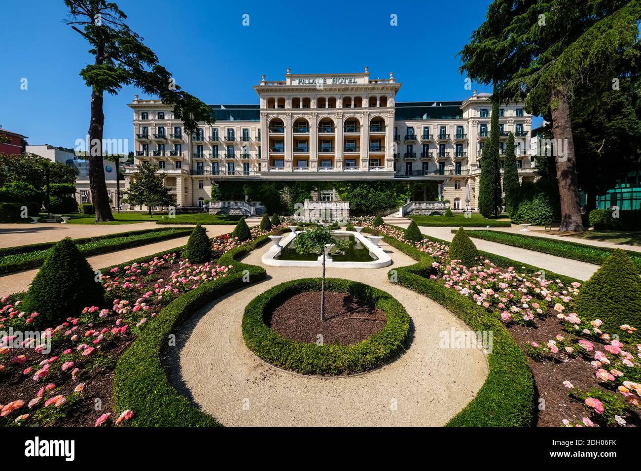 Vorderansicht des historischen Kempinski Palace Hotels mit gepflegtem französischem Garten und Blumenbeeten. Stockfoto