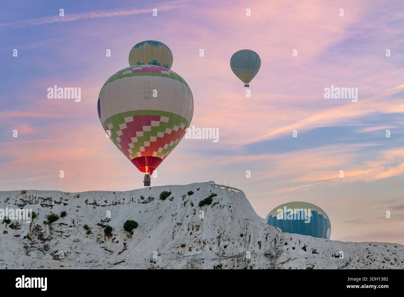 Heißluftballons fliegen bei einem farbenfrohen Sonnenaufgang in der Nähe des so genannten Baumwollschlosses in Pamukkale, Türkiye Stockfoto