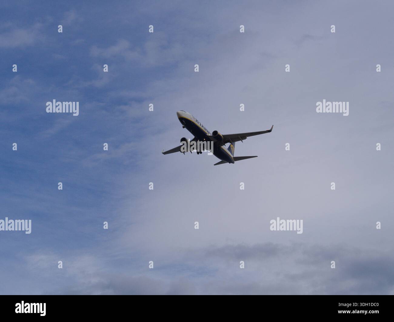 Das Flugzeug fliegt vor blauem bewölktem Himmel Stockfoto