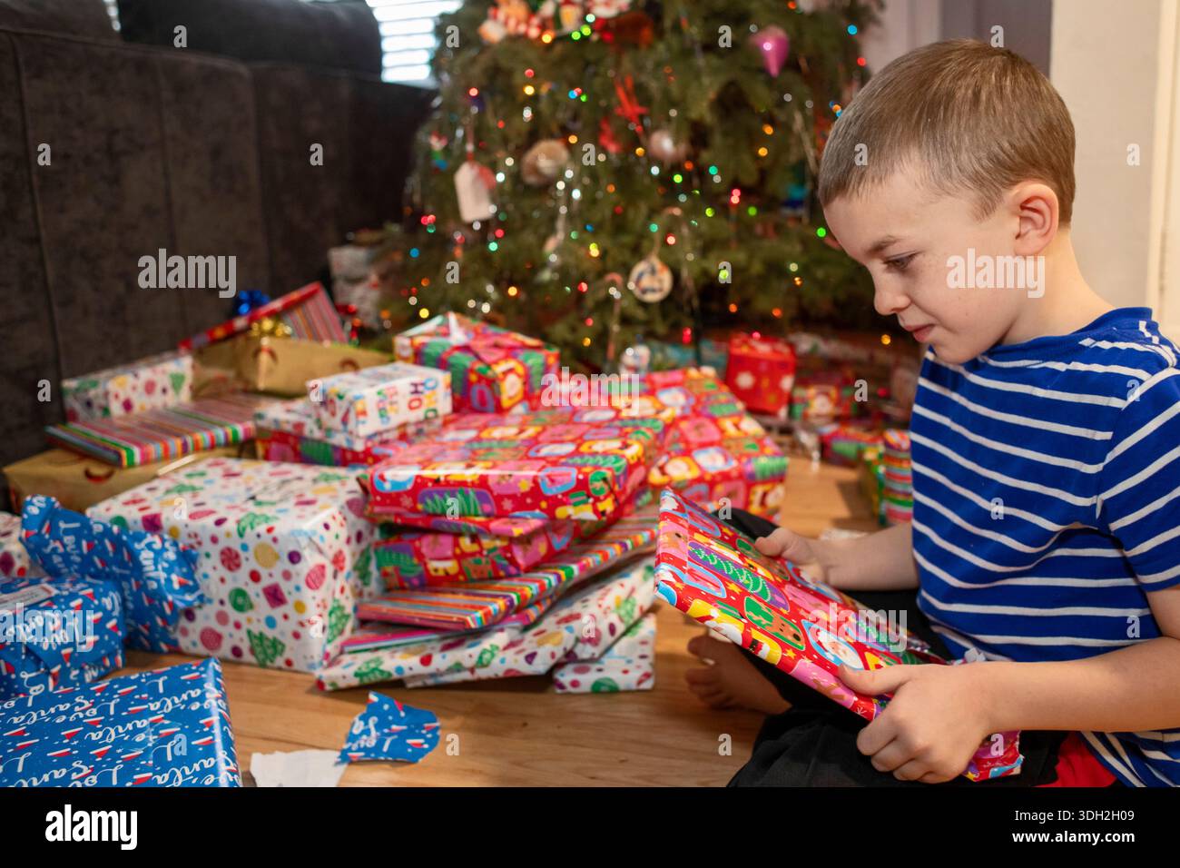 Denver, Colorado – Ein Junge öffnet Weihnachtsgeschenke am Weihnachtsmorgen. Stockfoto