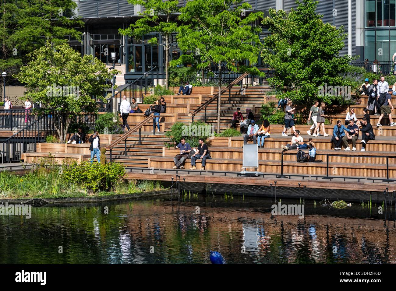 Menschen sündigen die Sonne im Eden Dock Park im Londoner Finanzviertel Canary Wharf. Stockfoto