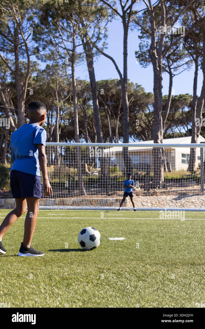 Afroamerikanische Jugendmänner üben Schuss auf Astrorasen in der Nähe von Tor mit Fußball, Kopierraum Stockfoto