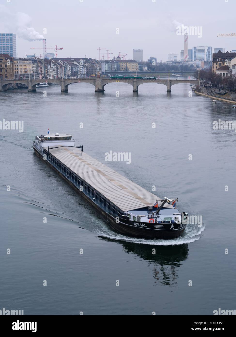 Ein kommerzielles Frachtschiff, das auf dem Rhein durch das Herz von Basel fährt Stockfoto