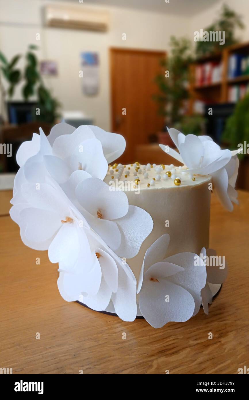 Weißer Kuchen mit Orchideendekorationen aus Papier für Feiern oder Hochzeiten, elegantes Dessert-Herzstück Stockfoto