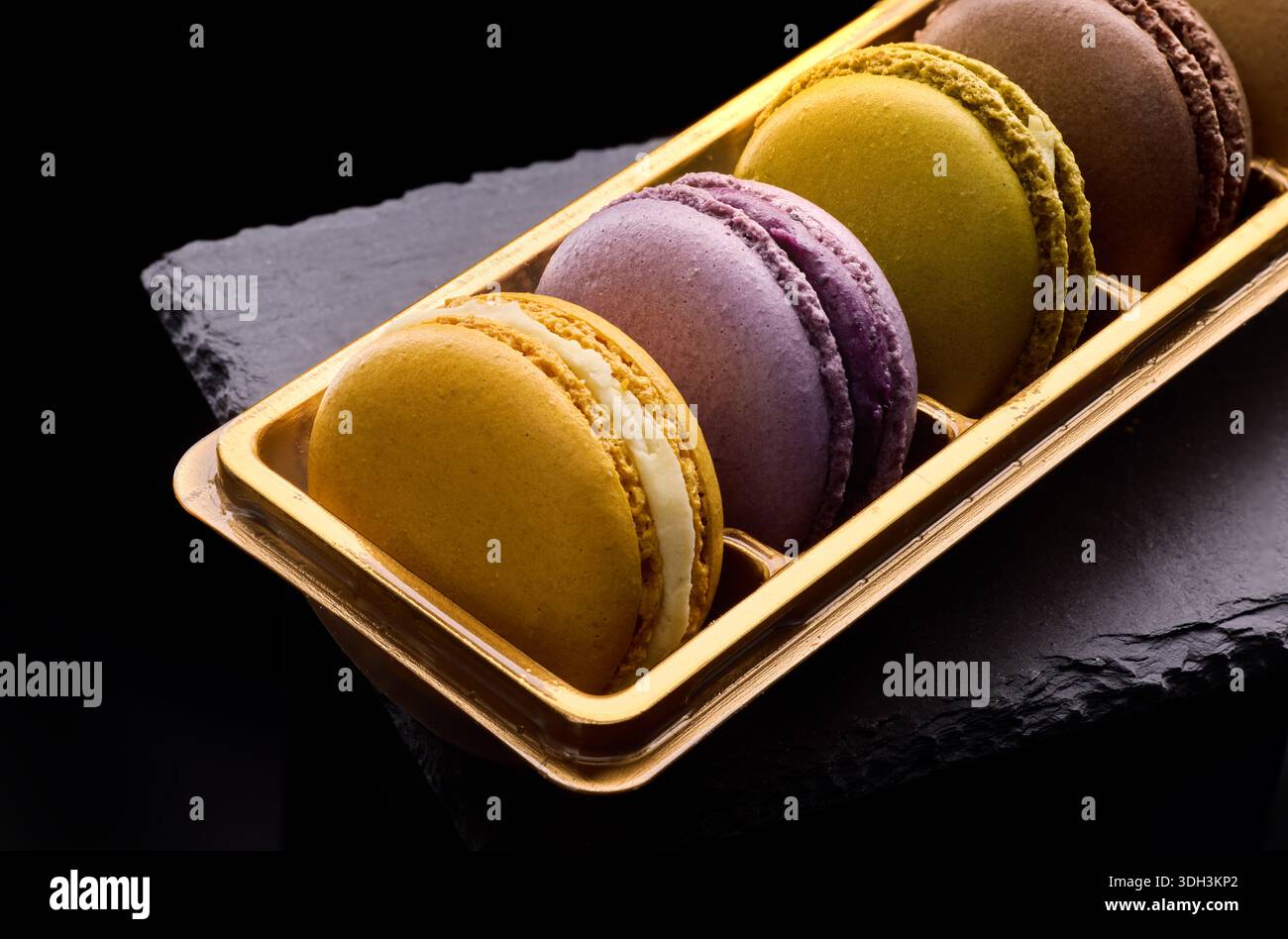 Bunte Macarons leckere Kekse auf schwarzem Hintergrund. Traditionelles französisches Dessert, Gourmet-Konditorei Stockfoto