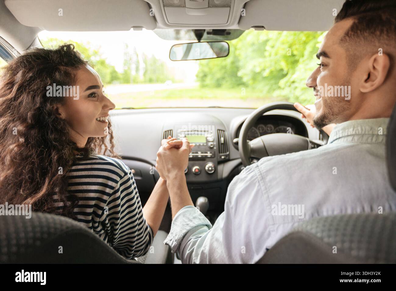 Liebevolles Paar, das die Hände hält, während es im Auto sitzt, Rückansicht Stockfoto