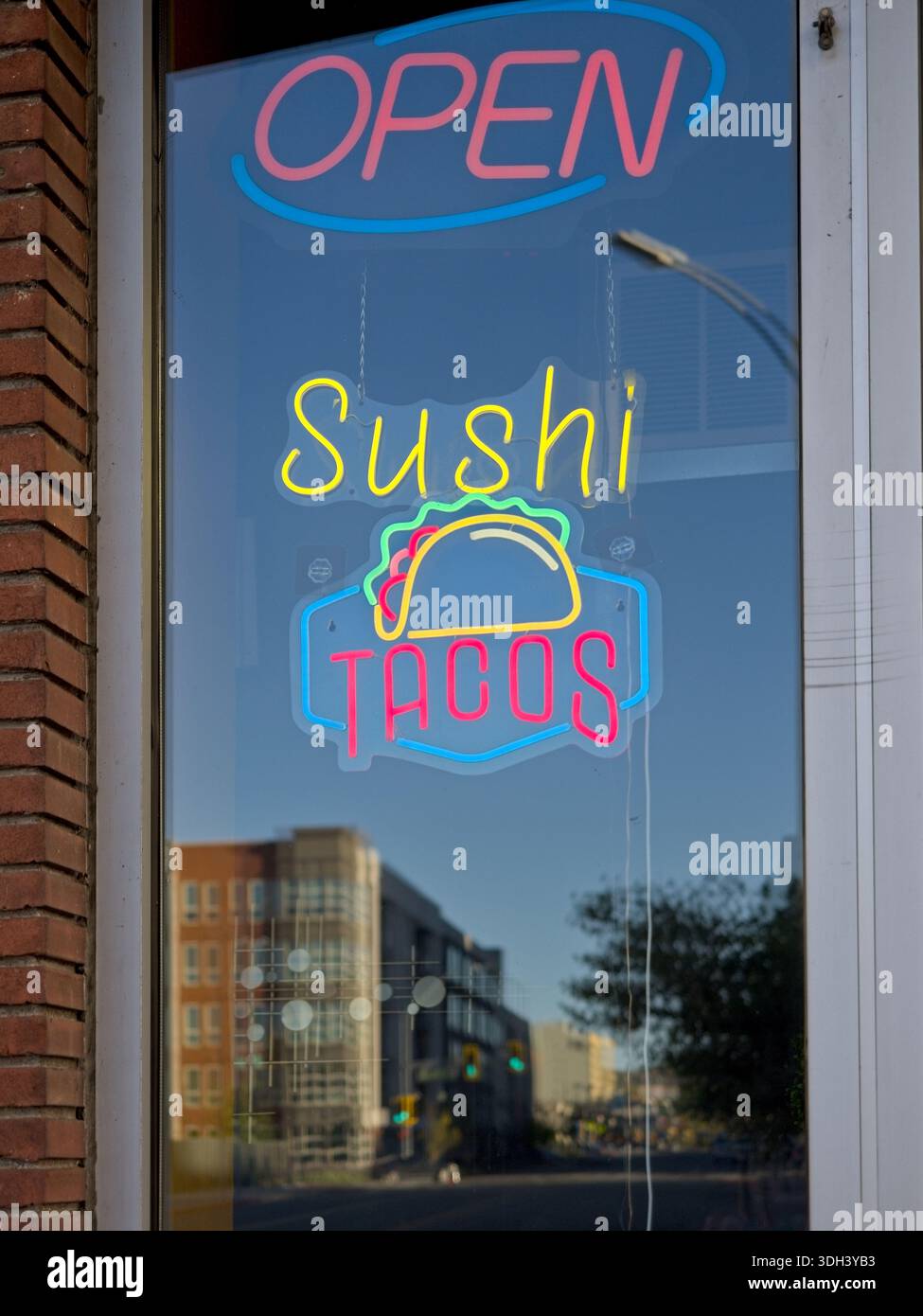 Neon-Sushi- und Tacos-Fensterschild mit Reflexionen der Straßenszene in Reno Nevada Stockfoto
