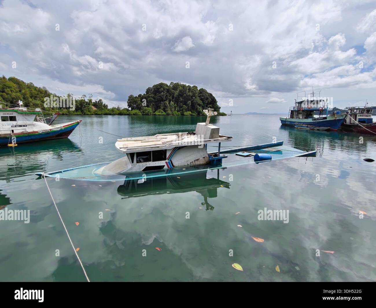Sabah, Malaysia - 13. Januar 2026: Ein dramatisches Bild eines weißen Motorbootes, das auf Wasser geht und teilweise in einer ruhigen, grünen Bucht sinkt. Andere Angelmöglichkeiten Stockfoto