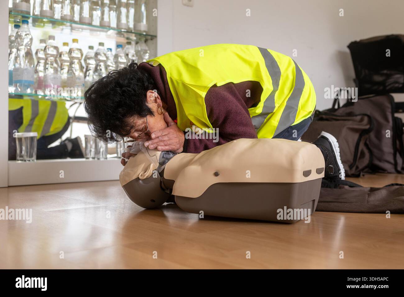Eine Person in einer Sicherheitsweste übt die HLW an einer Trainingskuppe aus. Das Bild zeigt das Wesen der erste-Hilfe-Schulung und hebt die wesentlichen LIFE hervor Stockfoto