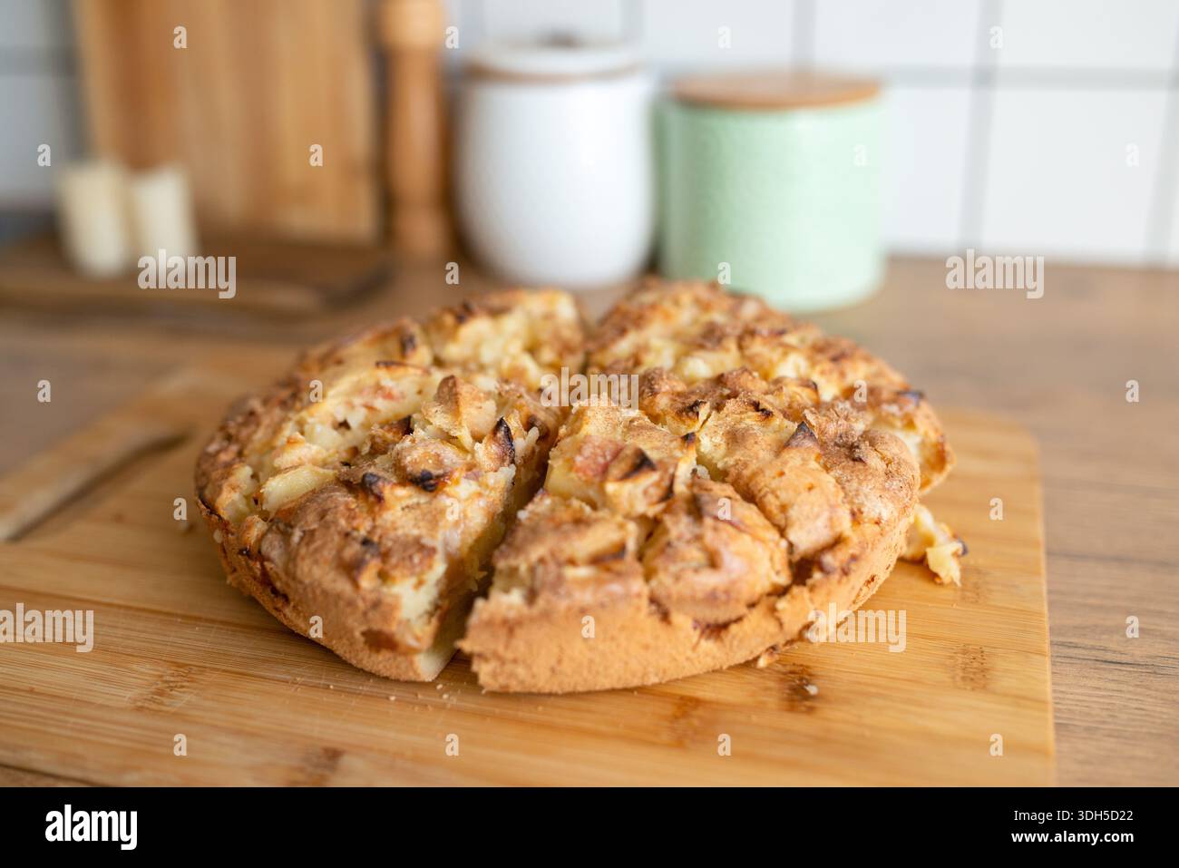 Eine Nahaufnahme eines frisch gebackenen, hausgemachten Apfelkuchen auf einem hölzernen Schneidebrett mit goldener Kruste und köstlichen Apfelstücken, perfekt für eine gemütliche Atmosphäre Stockfoto
