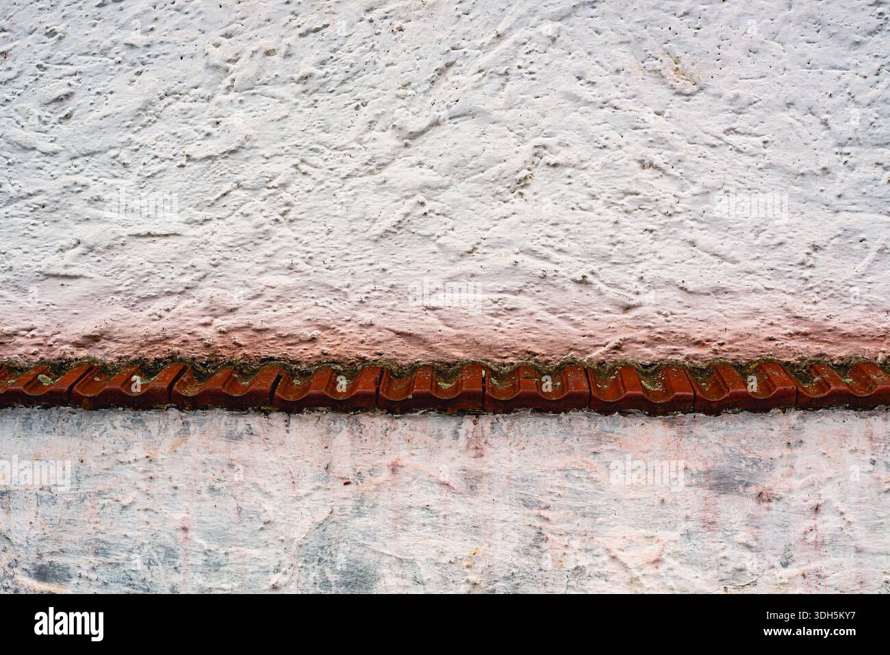 Weiße verputzte Wand mit rotem Ziegeldetail und rauer Textur Stockfoto