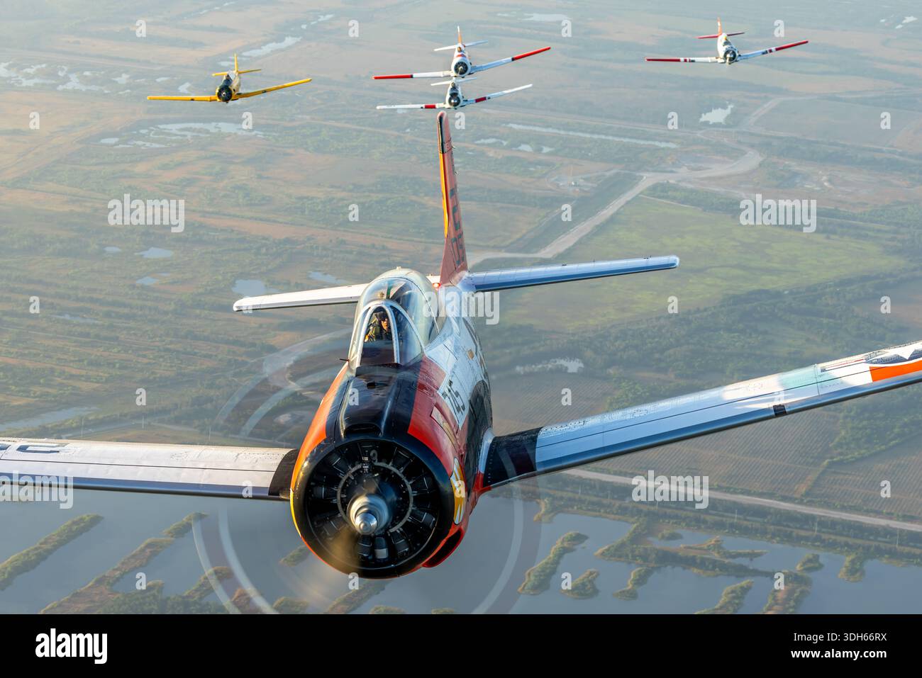 Formation Luft-Luft-Ansicht mehrerer nordamerikanischer Trainingsflugzeuge, darunter T-28C Trojan N745W VT-5, T-6G Texan N5451E, AT-6D Texan N7572, SNJ-5 Texan N5199V „Gotcha“ und AT-16 Harvard IIB N8994 auf der Sun N Fun Aerospace Expo 2025, Florida. Die Flugzeuge verfügen über Einzel-Radialmotoren, Tandemsitze, eine niedrige Flügelkonfiguration, ein einziehbares Fahrwerk und eine vollständige Kunstflugsteuerung für Trainingsflüge und leichte Demonstrationsflüge. Stockfoto