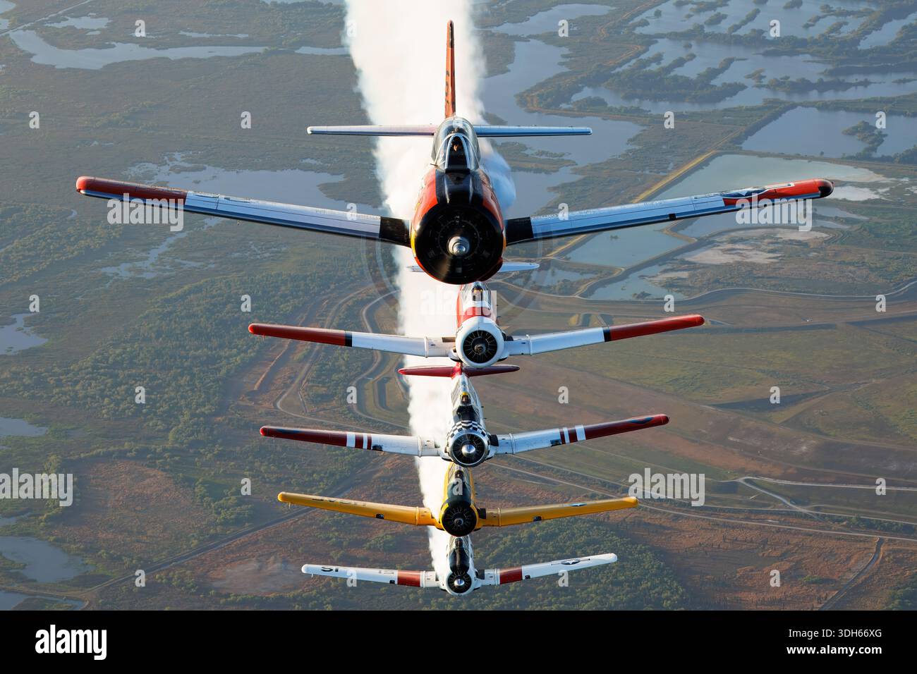 Dieser Formationsflug auf der Sun N Fun Aerospace Expo, Florida 2025, ist mit mehreren nordamerikanischen Trainerflugzeugen ausgestattet. Der T-28C Trojan, N745W, ist ein einmotoriger, kolbenmotoriger Militärtrainer mit US-Navy-Markierungen. Der T-6G Texan, N5451E, ist ein einmotoriger Fortgeschrittenentrainer mit US-Luftwaffe-Lack. Die AT-6D Texan, N7572, und SNJ-5 Texan, N5199V, enthalten Markierungen der südafrikanischen Luftwaffe und des Rennsports. Die AT-16 Harvard IIB, N8994, vervollständigt die Formation und führt koordinierte Rauchanzeigen im Luft-Luft-Flug durch. Stockfoto