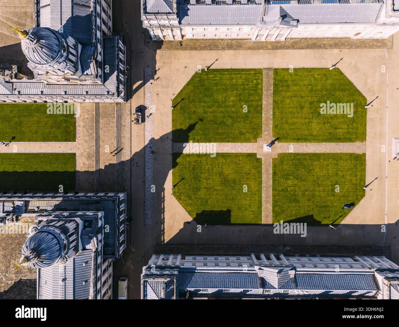 Luftaufnahme der symmetrischen, gepflegten Rasenflächen des Old Royal Naval College im Kontrast zu den scharfen Schatten und der komplizierten Architektur, London, Stockfoto