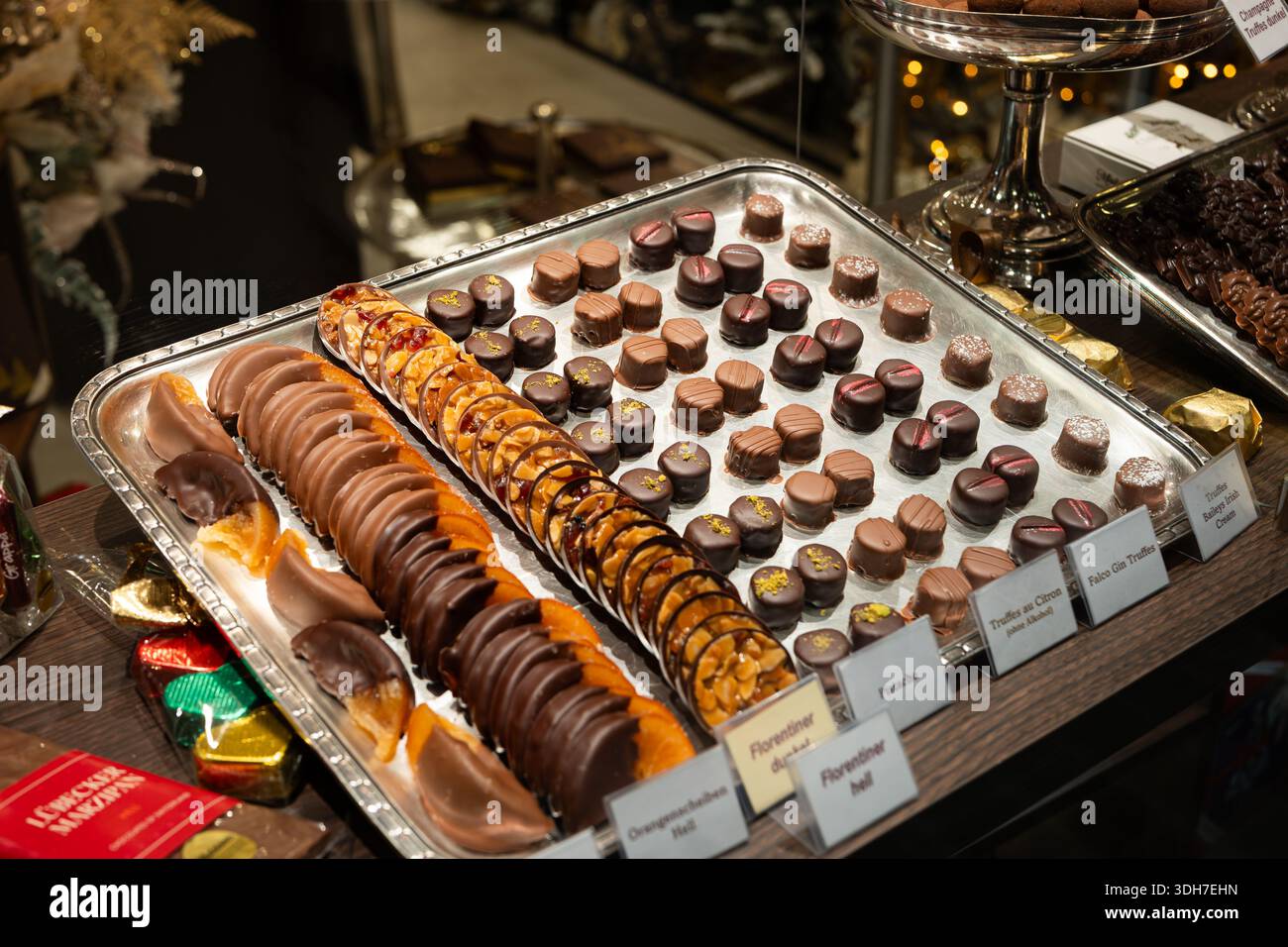Handgefertigte Schokoladenpralinen und Obstkuchen in einem Schaufenstershop. Nahaufnahme, Weitwinkelansicht, keine Personen Stockfoto