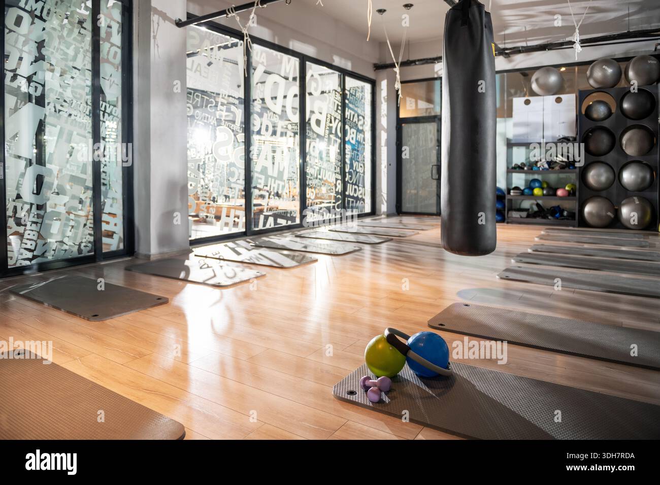Ein Foto von einem Yoga-Studio-Boden mit Spreizmatten, einer Matte mit zwei Kurzhanteln, zwei Pilates-Bällen und einem Pilates-Ring, der ordentlich für ein Fitness s angeordnet ist Stockfoto