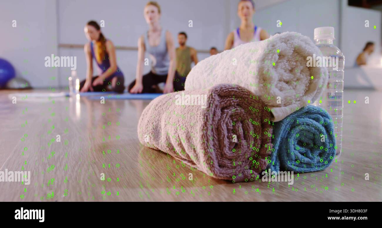 Im Yoga-Studio sitzen drei Handtücher auf dem Boden, mit einer Wasserflasche und kniend in sportlicher Kleidung Stockfoto