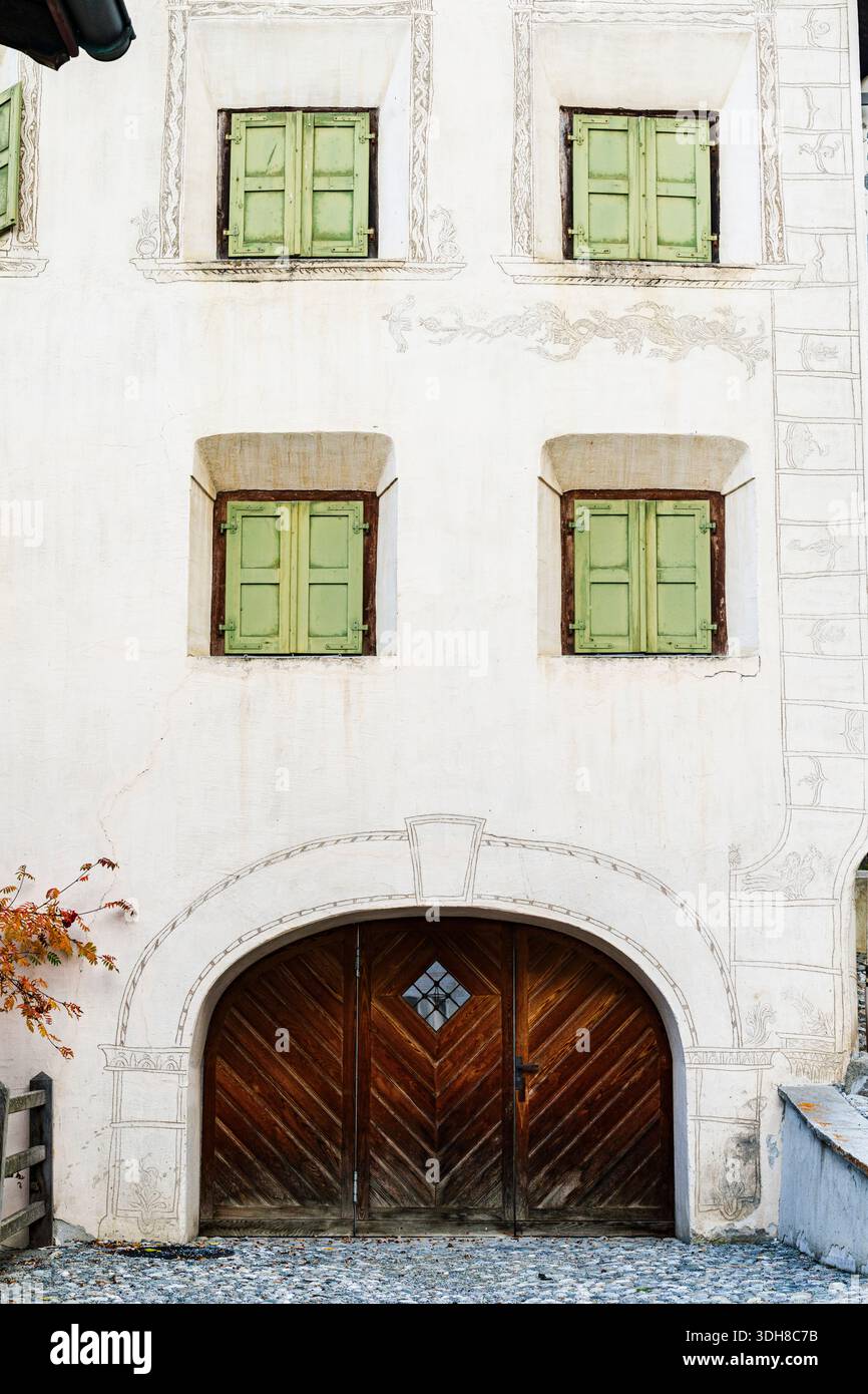 Alte Fassade mit grünen Fensterläden und Türöffnung, Ardez, Engadin, Graubünden, Schweiz Stockfoto