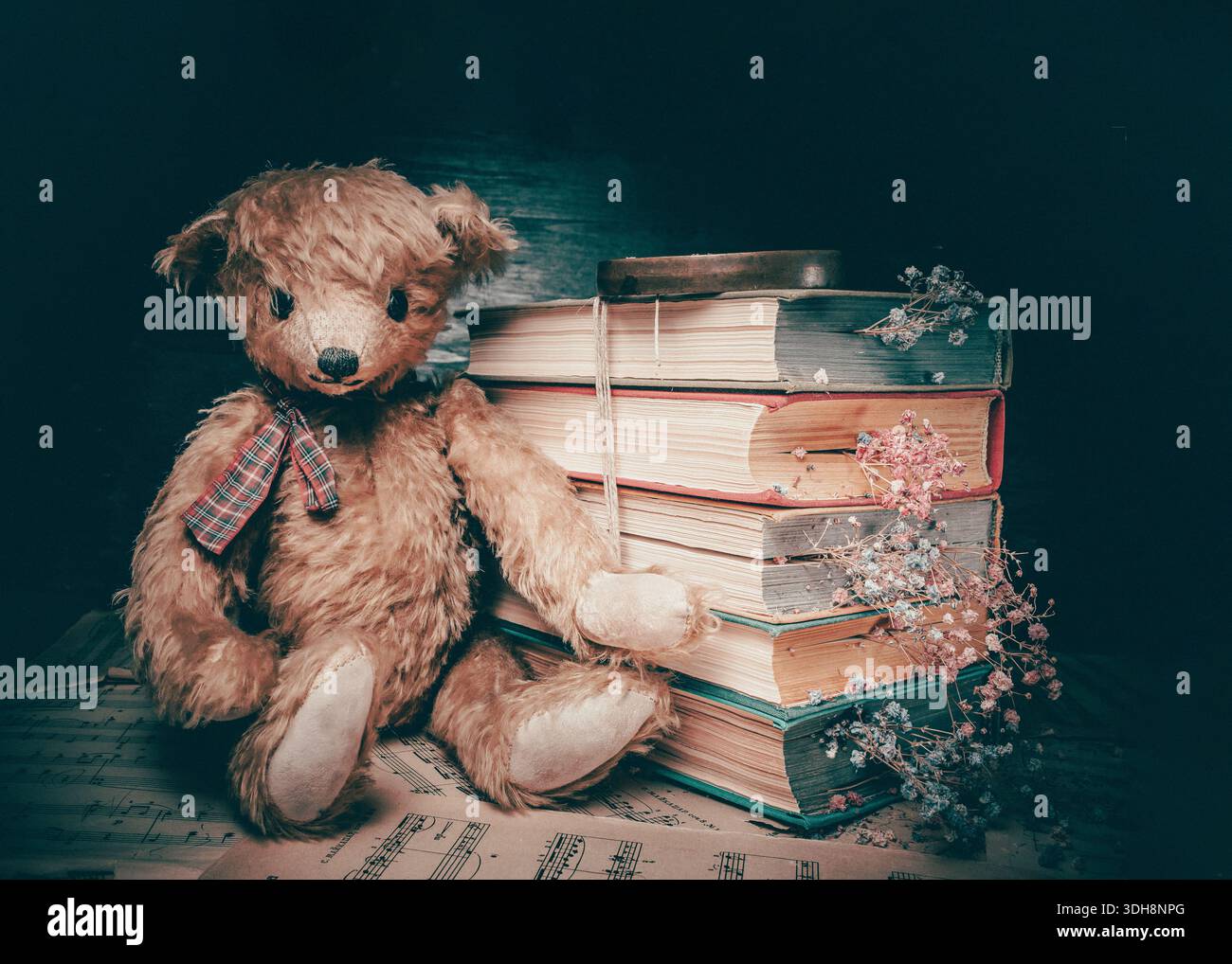 Vintage Teddybär, der neben alten Büchern sitzt, mit getrockneten Blumen auf gelben Seiten. Stillleben im Retro-Stil Stockfoto