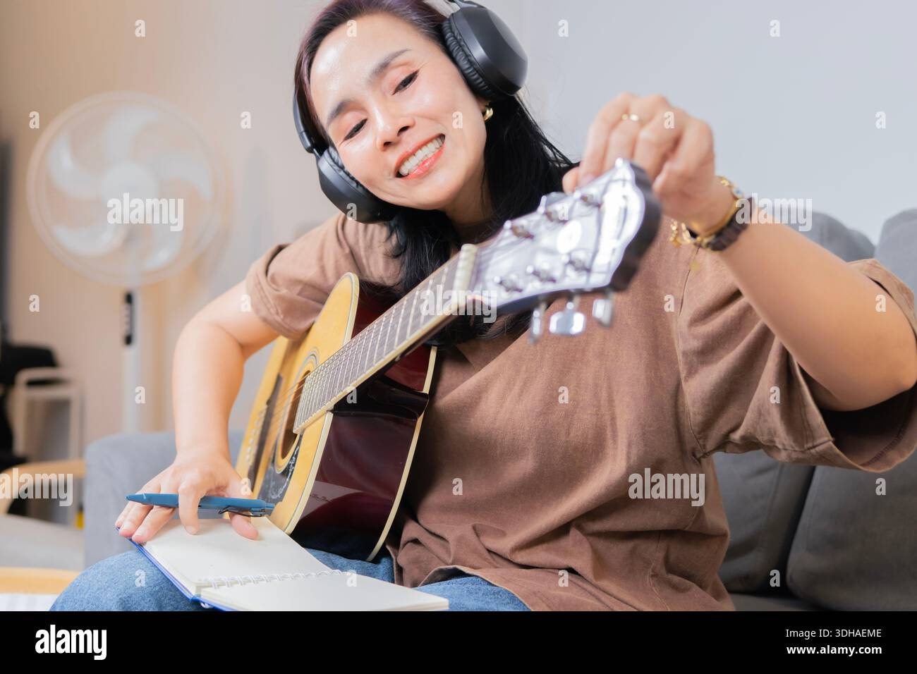 Songwriter, der Spaß hat, Hobbykonzept zu genießen und mit Akustikgitarre auf Notizpapier zu schreiben. Musikinstrument lernen. Stockfoto