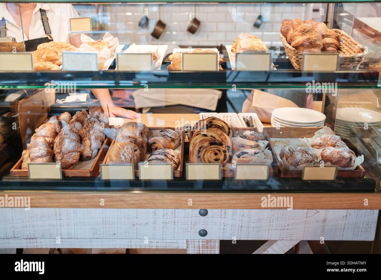 Vielfältige Auswahl an frisch gebackenen Croissants, Brötchen und süßem Gebäck in Backwaren-Glasvitrine Stockfoto