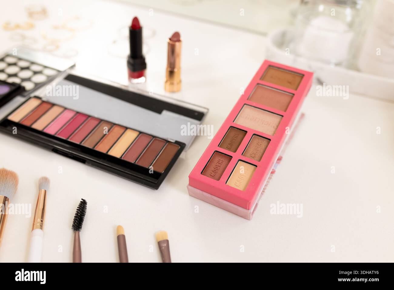 Make-up-Kosmetikbereich mit rosafarbenen sechs-Pan-Schattenpalette auf der rechten Seite mit Pinseln und Lippenstift, Kopierraum Stockfoto