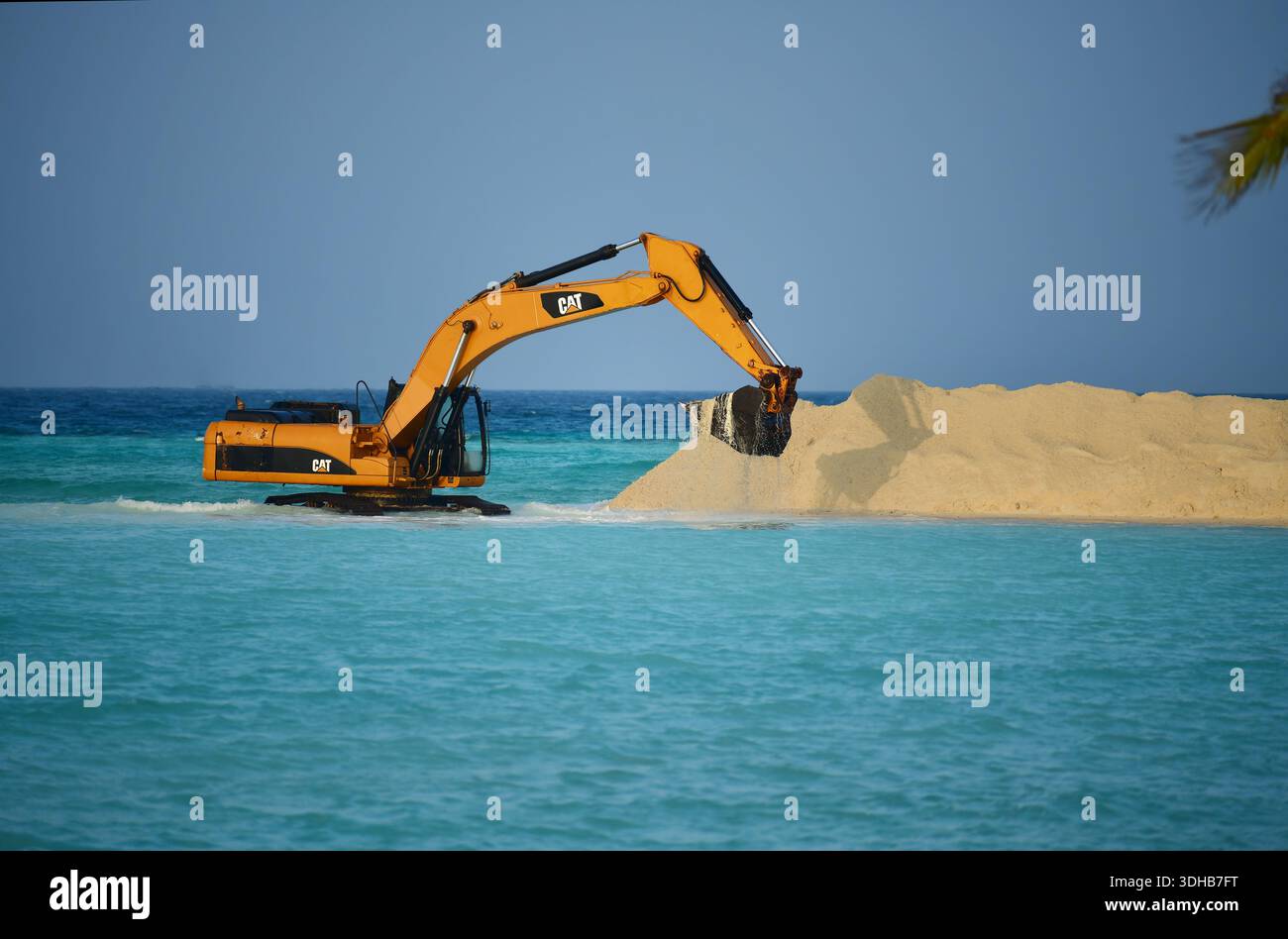 Gelber CAT-Caterpillar-Bagger, der Sand aus dem Meer im Rahmen einer Landgewinnung ausbaggert. Mathiveri Island, Malediven Stockfoto