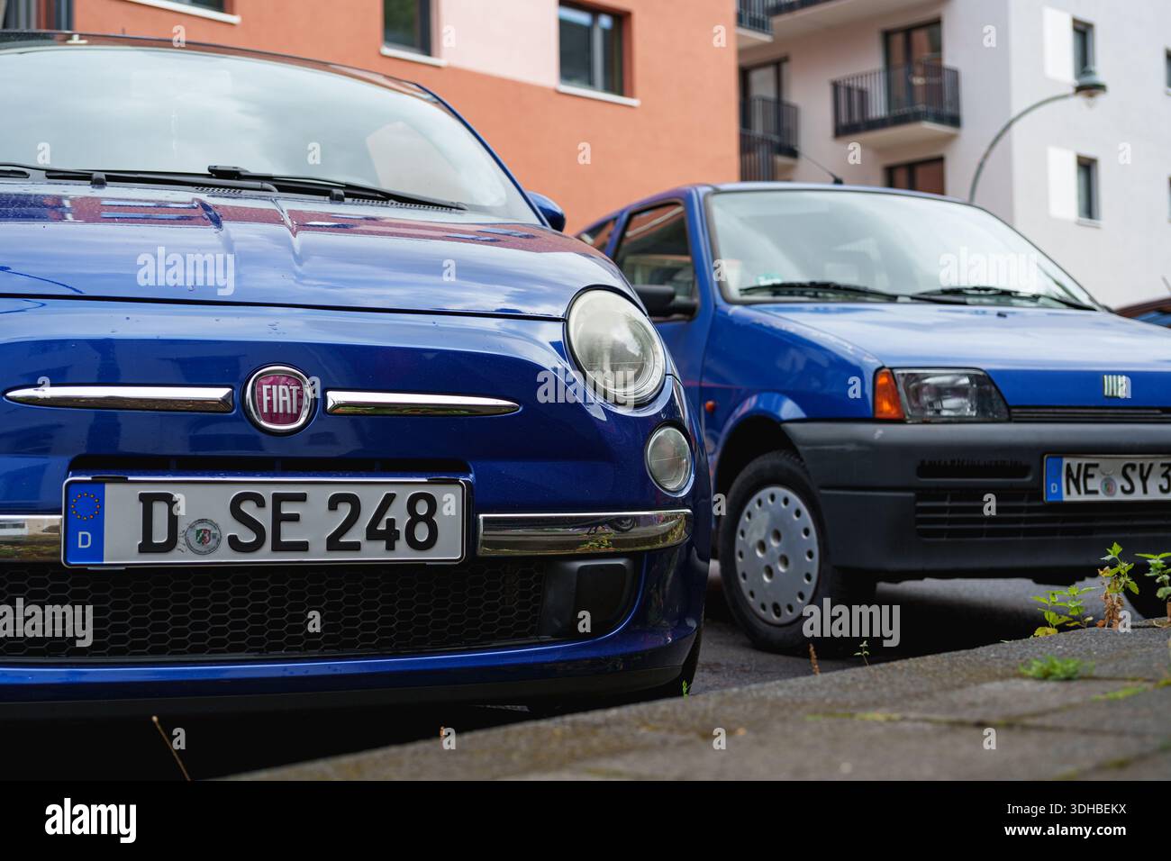 Alte und neue Fiat 500-Modelle parken zusammen auf einer Straße und zeigen zeitloses italienisches Design Stockfoto