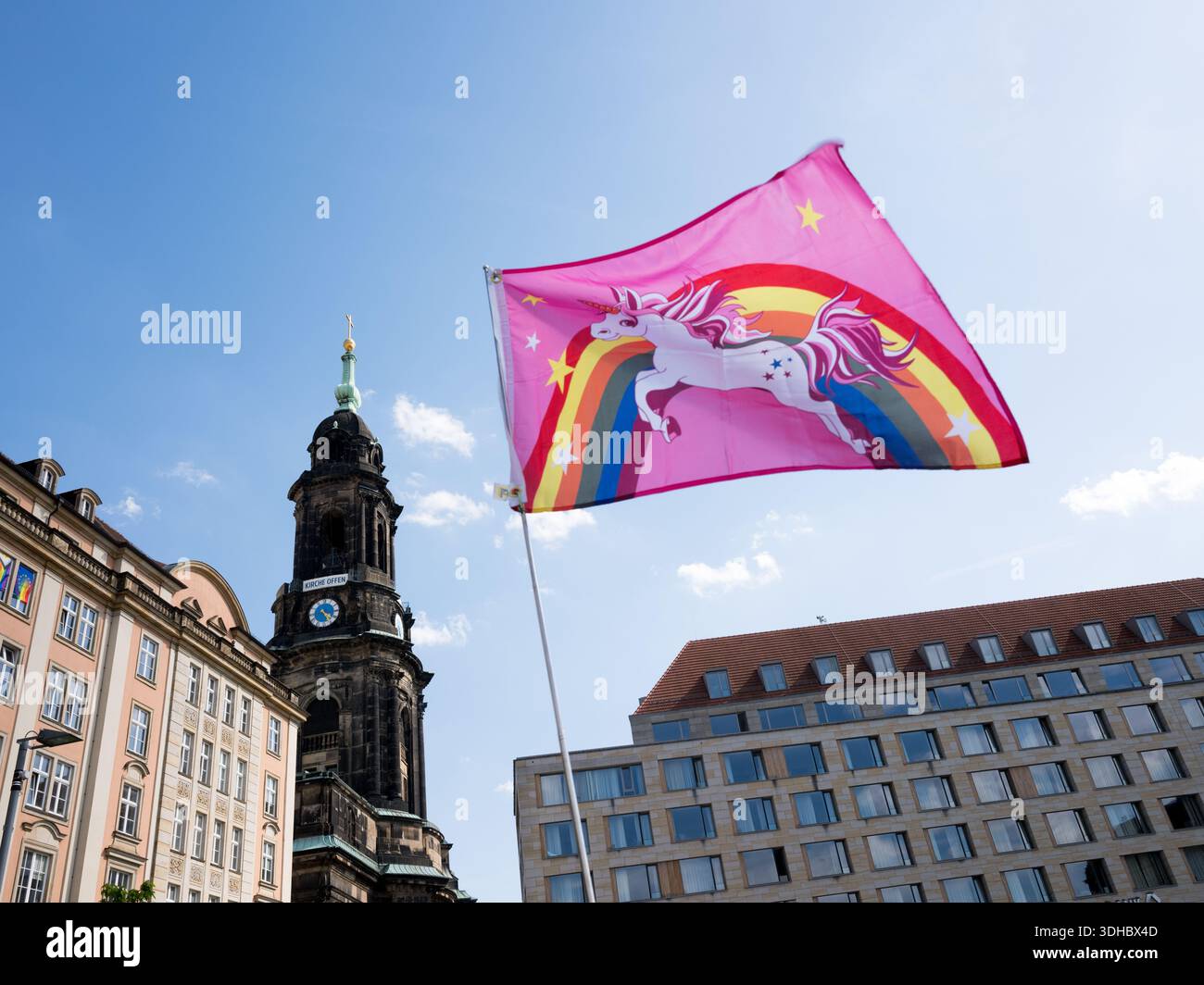Eine rosafarbene Flagge mit einem Einhorn und einem Regenbogen, die über dem Stadtzentrum von Dresden fliegen, mit dem historischen Kirchturm der Kreuzkirche. Stockfoto