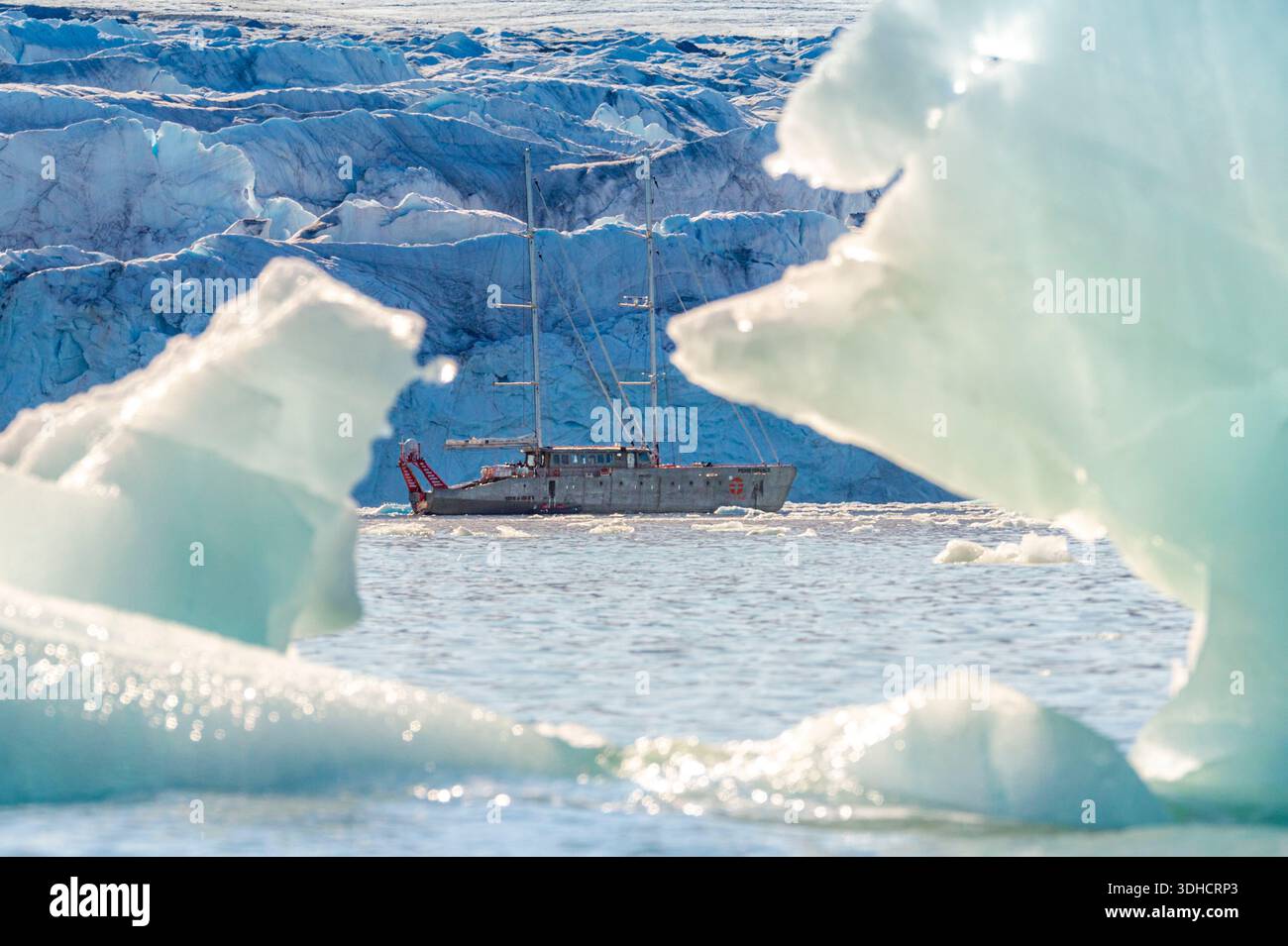 Norwegen, Svalbard-Archipel, Spitzbergen, Grönland, Krossfjord, Cross Bay, der wissenschaftliche Schoner Persévérance des Polarforschers Jean-Louis ETIENNE vor dem Gletscher vom 14. Juli (Fjortende Julibreen), der zwischen zwei treibenden Eisbergen zu sehen ist Stockfoto