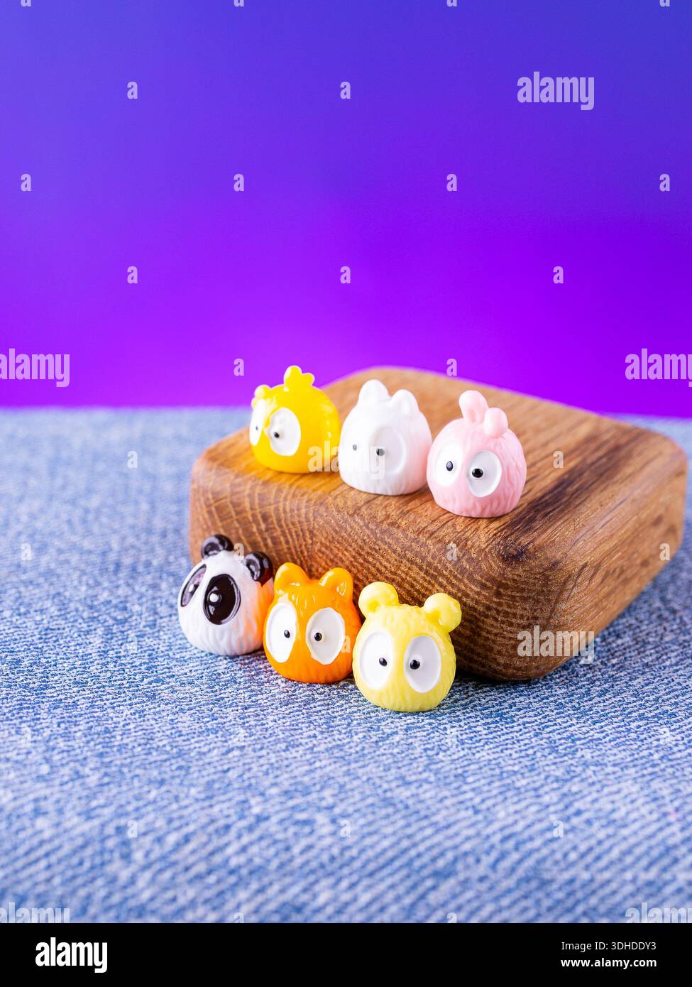 Eine Nahaufnahme einer Reihe von farbenfrohen, bezaubernden Tierfiguren im Kawaii-Stil, die auf einer Holzbühne platziert werden Stockfoto