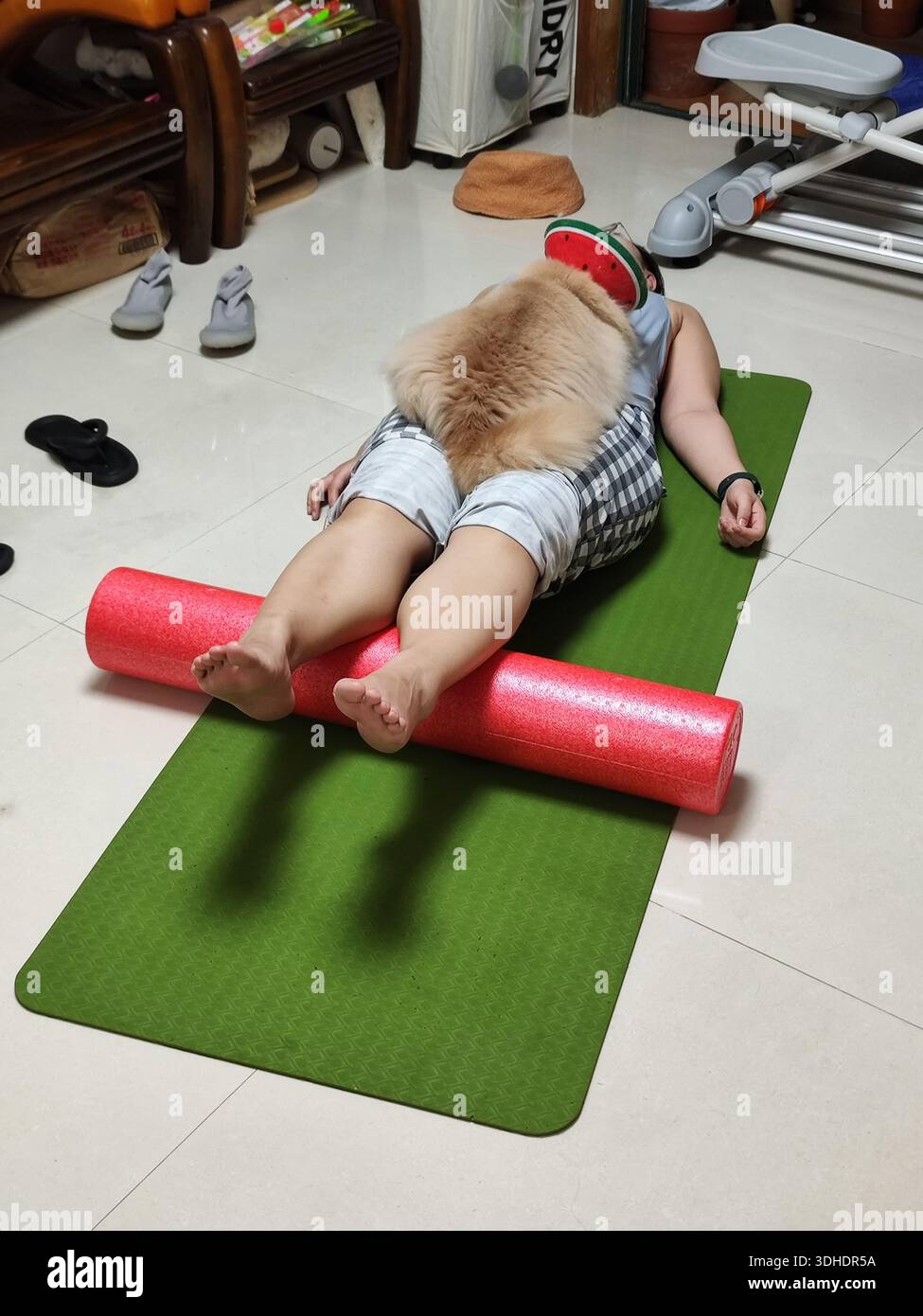 Eine Person, die Yoga macht, mit einem Hund, der auf den Beinen ruht Stockfoto
