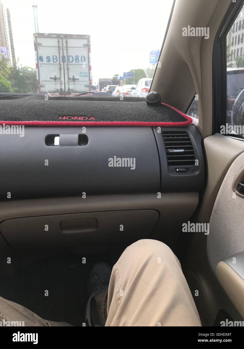 Innenansicht eines Armaturenbretts im Auto mit sichtbarem Fahrgastraum, Stadtverkehr im Hintergrund Stockfoto